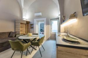 Dimora Suite Argento في غالّيبولي: مطبخ وغرفة معيشة مع طاولة وكراسي