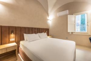 Dimora Suite Argento في غالّيبولي: غرفة نوم بها سرير أبيض كبير ونافذة