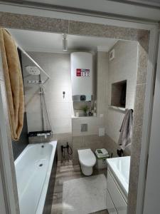 une salle de bain avec une baignoire, des toilettes et un lavabo dans l'établissement Уют 3, à Bishkek