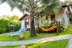 a house with a hammock and a palm tree at Pousada Reserva Penedo in Penedo