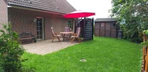 a patio with a table and a red umbrella at "Am Waldesrand" RE16 in Sögel