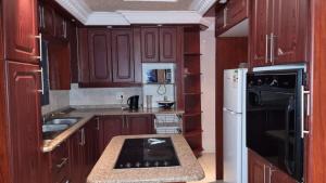 a kitchen with wooden cabinets and a white refrigerator at The Amazing Amazon Guesthouse in KwaMakhutha