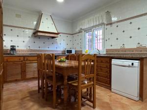 a kitchen with a wooden table with chairs and a white refrigerator at Chalet San Francisco in Sanlúcar de Barrameda