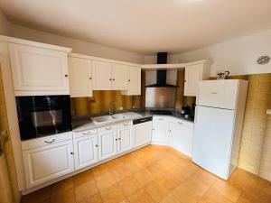 コロンビエールにあるMaison de Village Pres du Canalの白いキャビネットと白い冷蔵庫のあるキッチン