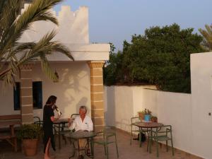 a woman standing next to a man sitting at a table at Hotel Villa Soleil in Sidi Kaouki