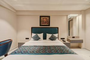 ein Schlafzimmer mit einem großen Bett und einem blauen Stuhl in der Unterkunft Hotel Royal Time in Ahmedabad + 62 Fotos