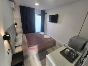 Una pequeña habitación con una cama y un televisor. en Alex Residence, en Otopeni
