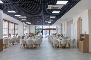 Tek Hotel Mürefte في Şarköy: غرفة طعام مع طاولات بيضاء وكراسي بيضاء