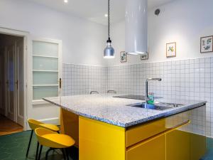 a kitchen with a sink and two yellow chairs at Tyzenhauz Grand Apartaments in Kraków +59 photos