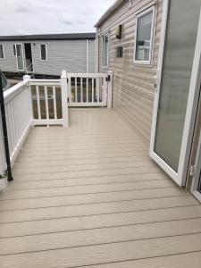 a deck with a white railing and a house at Dog Friendly 6 Berth Caravan With Decking Close To Pakefield Beach Ref 68106Cr in Pakefield +1 photo