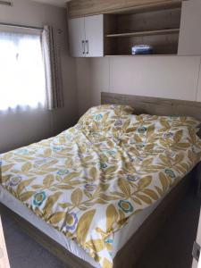 a bedroom with a bed with a yellow and blue comforter at Dog Friendly 6 Berth Caravan With Decking Close To Pakefield Beach Ref 68106Cr in Pakefield