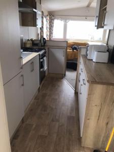 a kitchen with white cabinets and a wooden floor at Dog Friendly 6 Berth Caravan With Decking Close To Pakefield Beach Ref 68106Cr in Pakefield