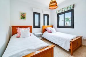 two beds in a room with two windows at 4 Bedroom Villa With Private Pool in Maroni +43 photos