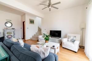 a living room with a blue couch and white chairs at 4 Bedroom Villa With Private Pool in Maroni