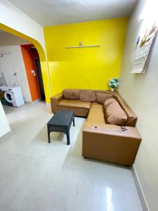 ein Wohnzimmer mit einem braunen Sofa und einer gelben Wand in der Unterkunft Home stay B1 Groundfloor in Chennai + 3 Fotos