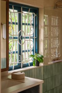 a bathroom with a window with a plant on a counter at Sanctuary by RÊVE in Siolim +31 photos