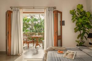 a bedroom with a bed and a balcony with a table at Sanctuary by RÊVE in Siolim
