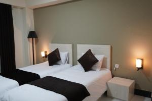 two beds in a room with white sheets and pillows at Herat Star Hotel in Herāt +57 photos