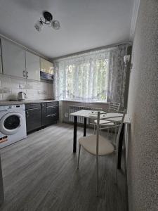 a kitchen with a table and a chair and a table and a microwave at Buiucani in Chişinău