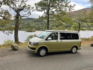 a green and white van parked next to a lake at Campervan Scotland, Ben Roamer in Dunblane