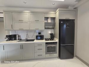 a kitchen with white cabinets and a stainless steel refrigerator at Luxuriöse Ferienwohnung in Manavgat ilica in Ilıcaköy
