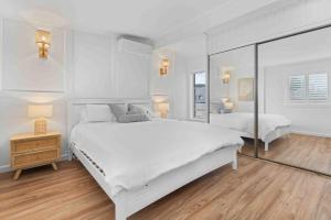 ein weißes Schlafzimmer mit 2 Betten und Holzboden in der Unterkunft 5 Bedroom Pet Friendly Home - 50m to Culburra Beach in Culburra Beach