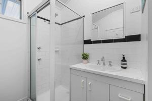 ein weißes Badezimmer mit Waschbecken und Dusche in der Unterkunft 5 Bedroom Pet Friendly Home - 50m to Culburra Beach in Culburra Beach + 20 Fotos