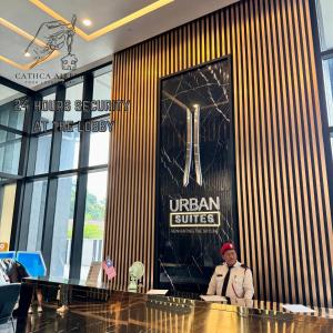 a man sitting at a counter in front of an urban suites sign at Urban Suites 2BR #SelfCheck-in #6Pax #TopFacilities in Jelutong +66 photos