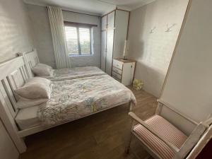 a small bedroom with a bed and a chair at Klipwerf in Struisbaai