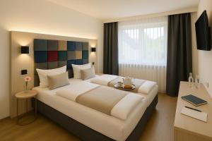 a bedroom with a large white bed and a desk at Messehotel Daucher A9 Autobahn 24h Self-Check-in in Nuremberg