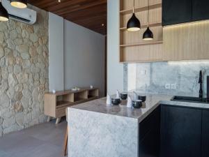 a kitchen with a marble counter top and wooden cabinets at LM Home 2 Mendira in Candidasa