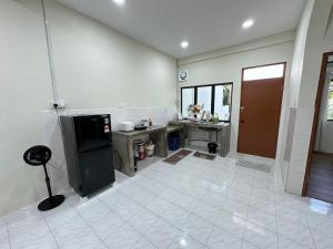 a large kitchen with a black refrigerator and a tile floor at Permaisuri homestay in Bintulu