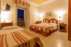 
a hotel room with two beds and two lamps at Mariano IV Palace Hotel in Oristano
