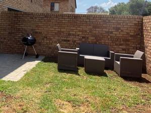 a wall with chairs and a grill in a yard at Yanaz Place in Germiston