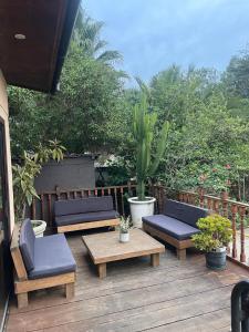 a wooden deck with benches and a table and chairs at Casa en la playa con piscina in Guanaquero