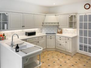 a white kitchen with white cabinets and a sink at Aspen Grove Lodge in Sutton