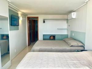 una camera da letto con due letti e una TV a parete di Flat JP Beira mar a João Pessoa Altre 34 foto