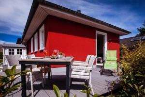 a patio with a table and chairs and a red wall at Ferienhaus Sandseele in Fehmarn