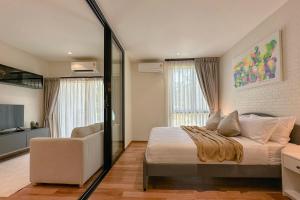 a bedroom with a bed and a couch and a television at Modern 1 & 2 Bedroom Apartments Naiyang Phuket by Mango Family in Nai Yang Beach +57 photos