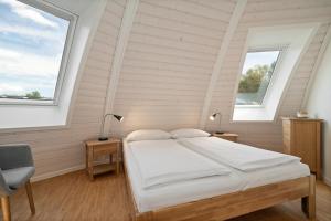Un dormitorio con una cama y dos ventanas. en Kugelhaus Phoebe Charmantes Kugelhaus aus Holz am Waldrand des Tollensesees, en Wustrow