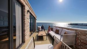 a couple standing on a balcony looking at the ocean at Hüs Hallig Luk Wohnung 1 in Wyk auf Föhr