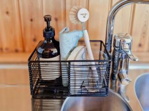 a basket of kitchen utensils sitting on a sink at Charming Cottage Near The Sea On Rossö in Nyckleby +22 photos