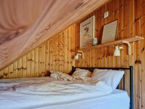 a bedroom with a wooden wall with a bed at Charming Cottage Near The Sea On Rossö in Nyckleby