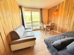 a room with a couch and a table and a dining room at Le Balcon du Bois in Le Dévoluy