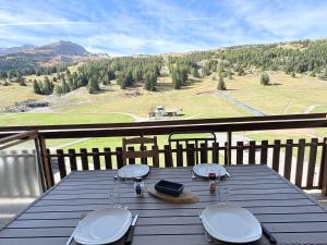 a table on a deck with a view of a mountain at Le Balcon du Bois in Le Dévoluy