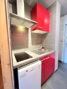 a small kitchen with red cabinets and a sink at Le Balcon du Bois in Le Dévoluy +2 photos