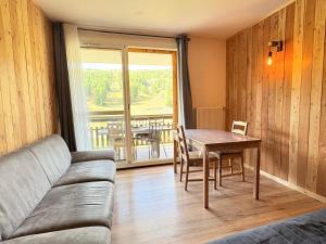 a living room with a couch and a table at Le Balcon du Bois in Le Dévoluy