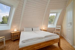 a bedroom with a bed and two windows at Kugelhaus Chiara - Helles Naturrefugium in Kugelform am Tollensesee in Wustrow