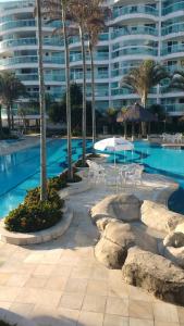 Una piscina con sillas y una mesa y un edificio. en Apartamento Pontal Beach., en Río de Janeiro