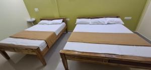 two beds in a room with green walls at A J Home Stay in Tiruvannāmalai